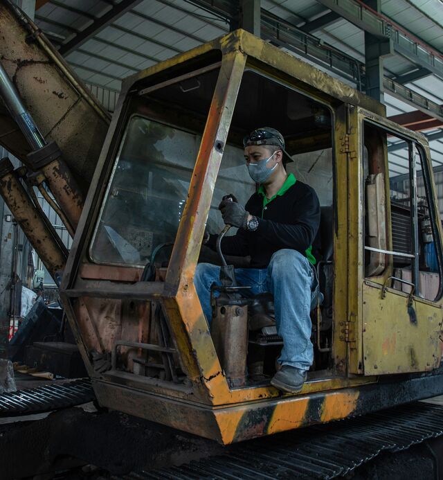Een oude graafmachine in een werkplaats, een technieker zit in de cabine